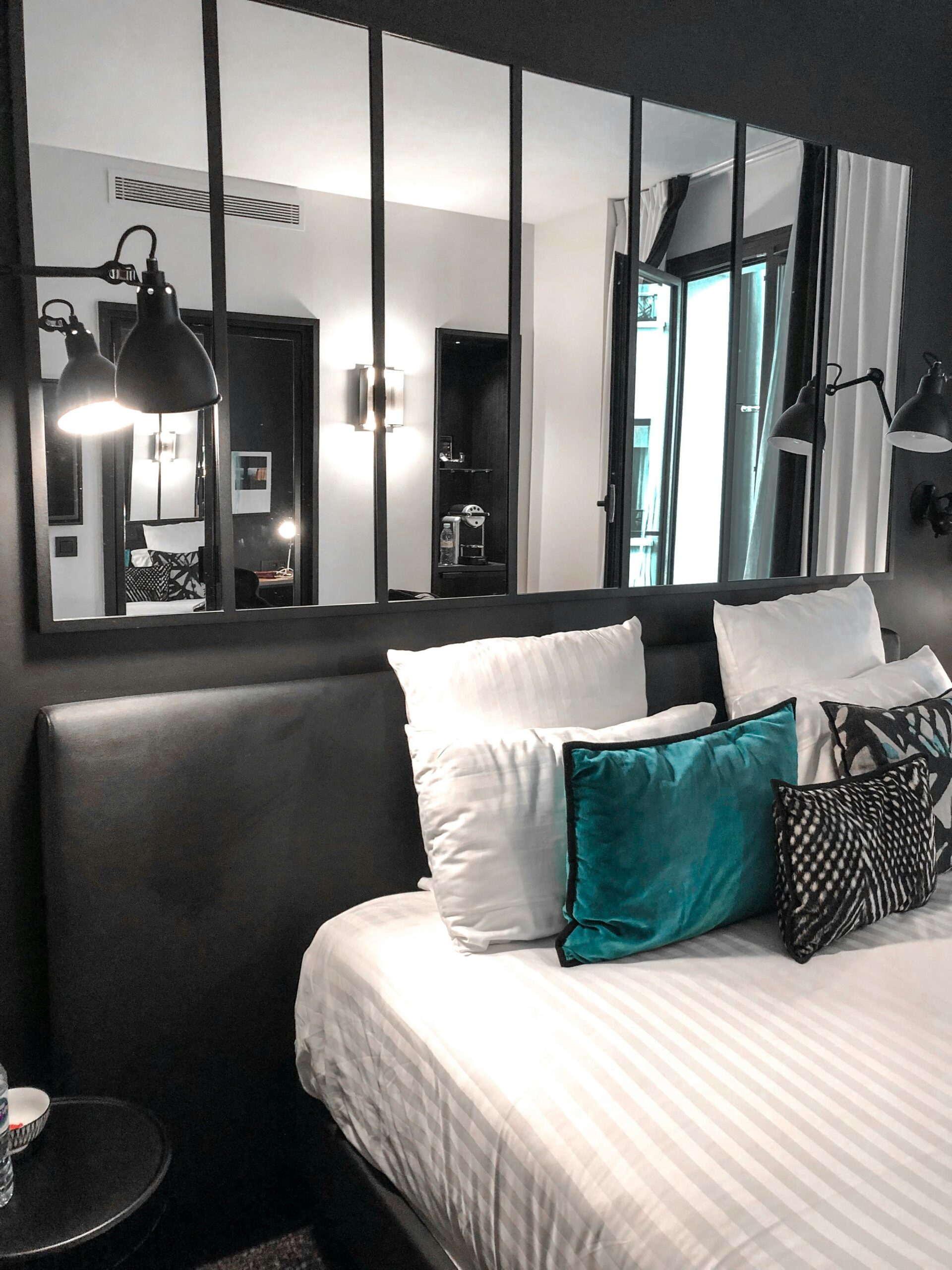 Stylish bedroom featuring modern decor, plush pillows, and large mirrors enhancing the space.