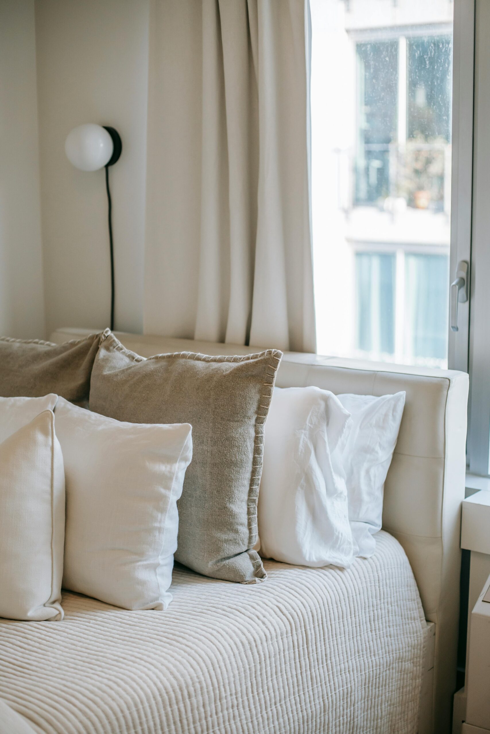 A serene and cozy bedroom setup featuring soft linen cushions and natural light.